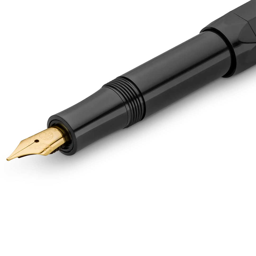 Close-up of a glossy black fountain pen nib and upper barrel with a gold-tone nib, shown on a clean white background.