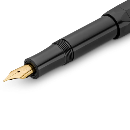 Close-up of a glossy black fountain pen nib and upper barrel with a gold-tone nib, shown on a clean white background.