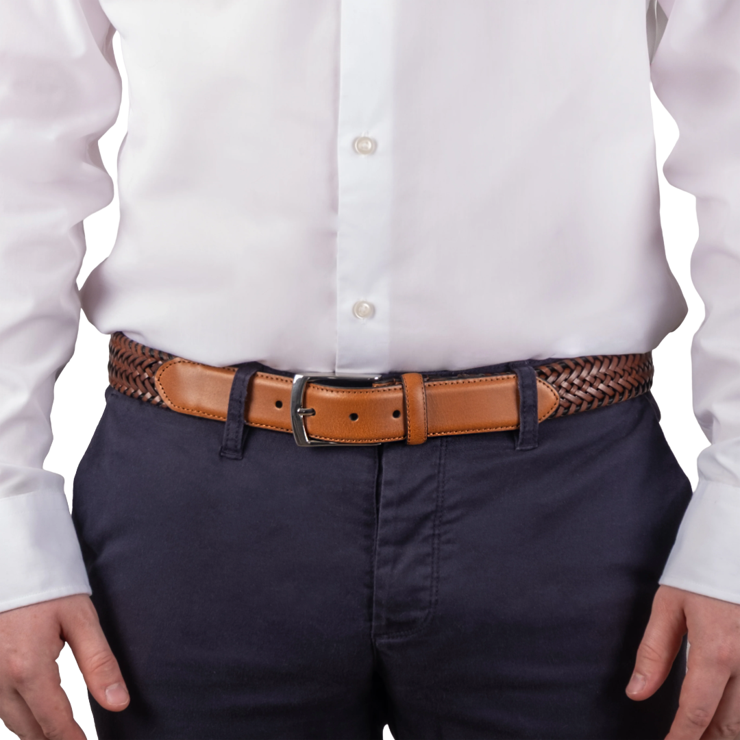 A close-up of a person wearing a white dress shirt, navy pants, and a tan leather belt with a braided brown-and-black waistband, shown against a plain white background.