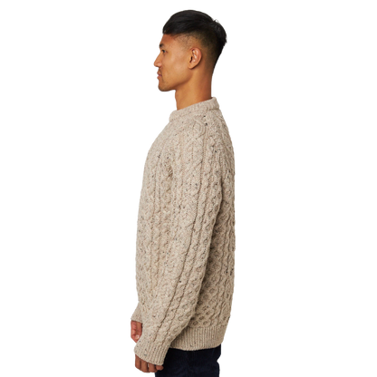 A man shown in profile wearing a beige cable-knit sweater against a plain white background.