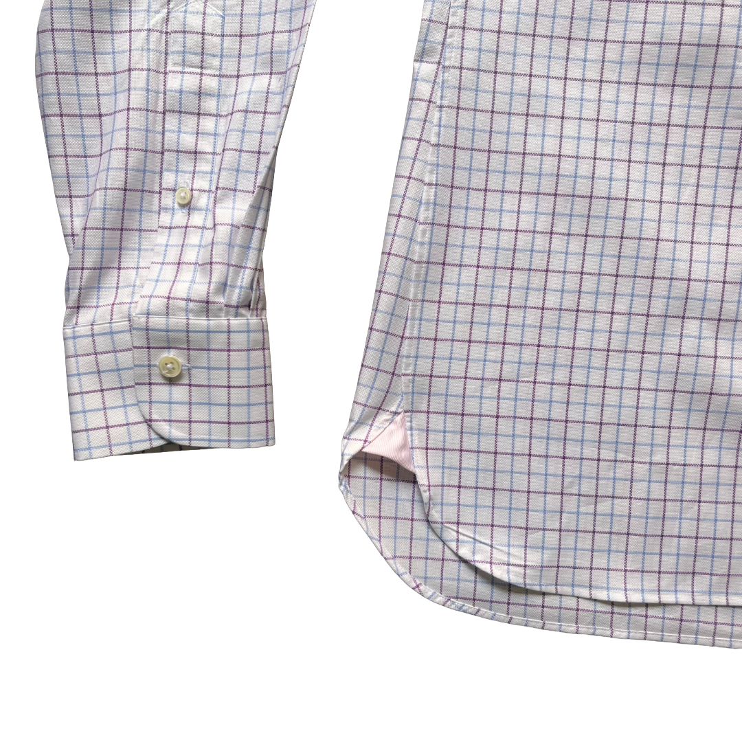 Close-up of a long-sleeve button-up shirt showing the sleeve cuff and main body, featuring a fine windowpane check pattern in light blue and burgundy on a white base.