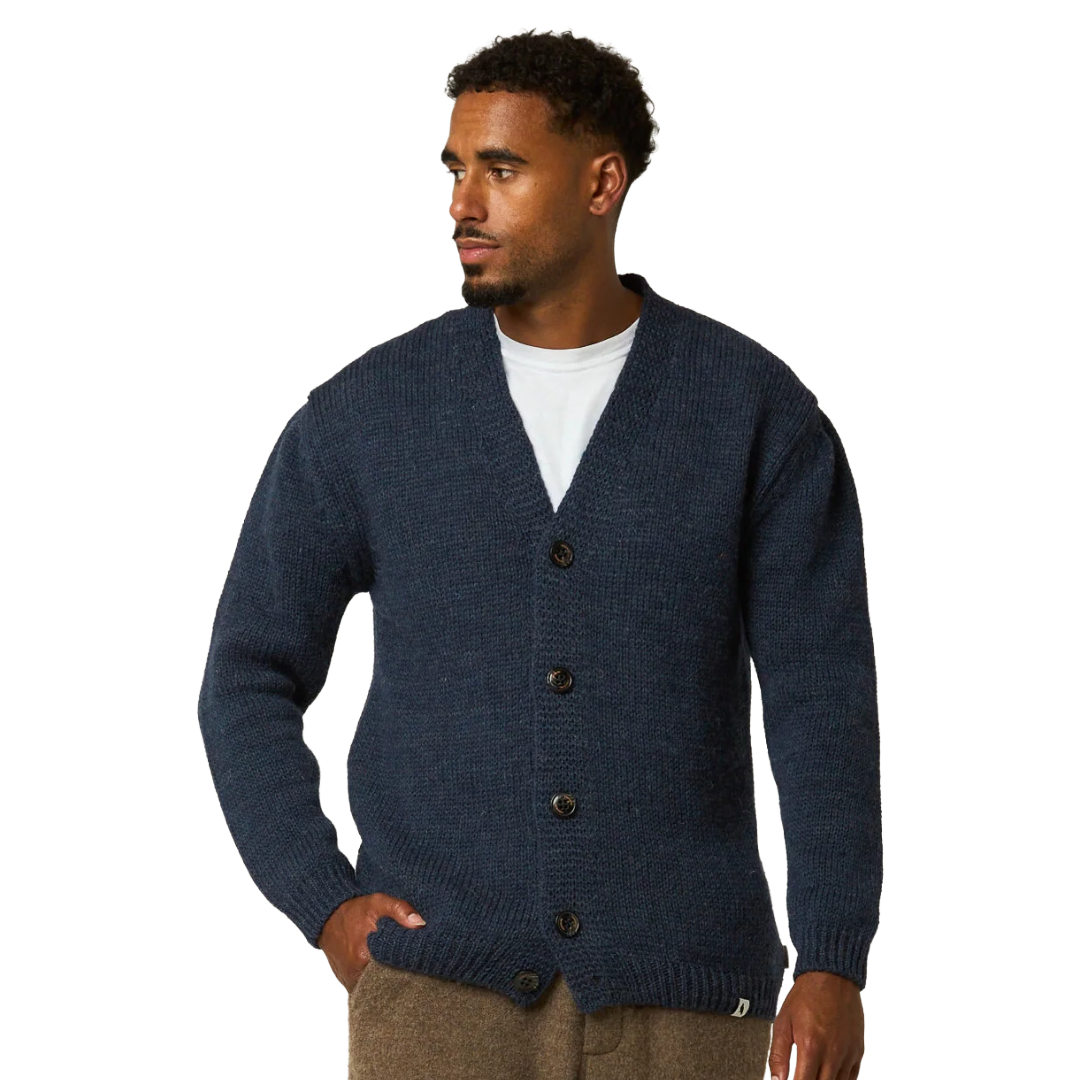 A man wearing a navy blue ribbed knit cardigan over a white t-shirt and brown pants, photographed against a solid white background.