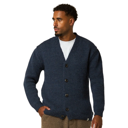 A man wearing a navy blue ribbed knit cardigan over a white t-shirt and brown pants, photographed against a solid white background.