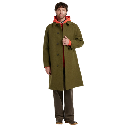 A man modeling a long olive green wool-blend coat over a bright orange hoodie, brown pants, and brown shoes, photographed against a solid white background.