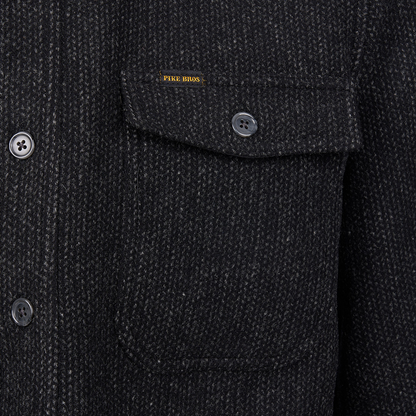 Close-up of a dark charcoal tweed jacket with a chest pocket, button flap, and a small yellow Piqué Boss label.