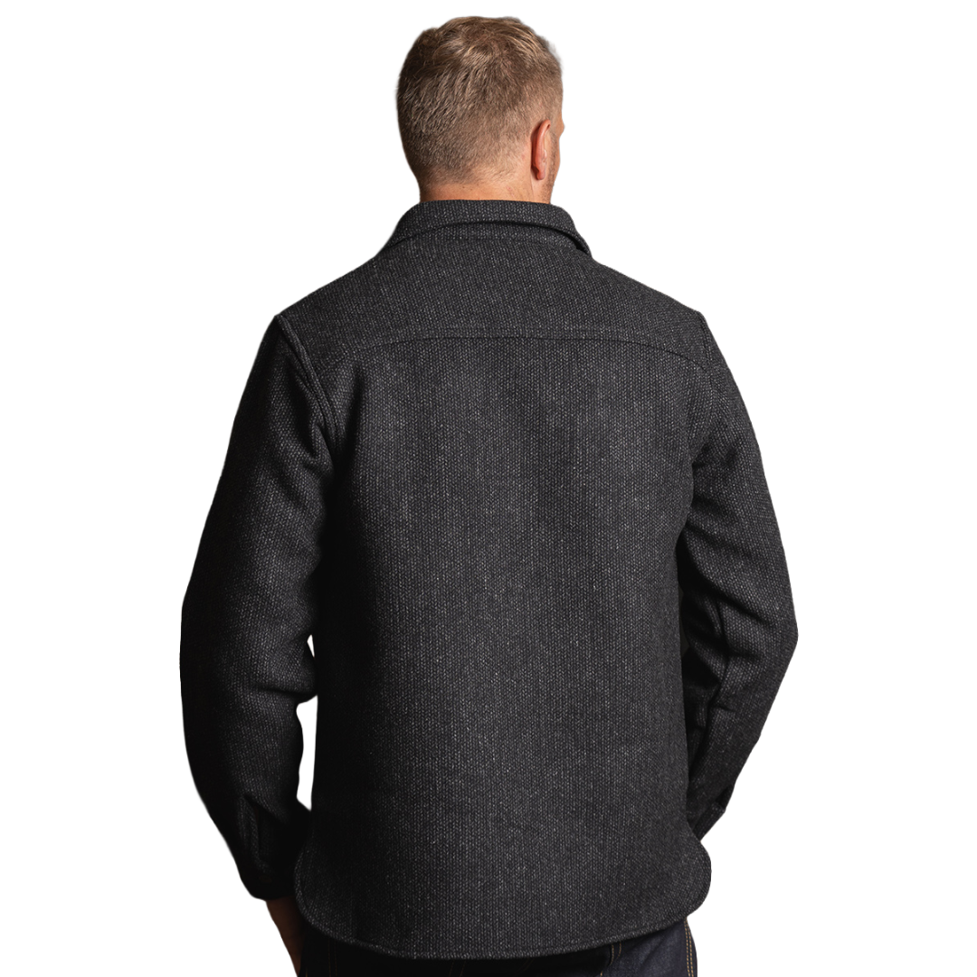 A man viewed from the back wearing a dark charcoal gray textured overshirt or jacket, shown against a plain white background.