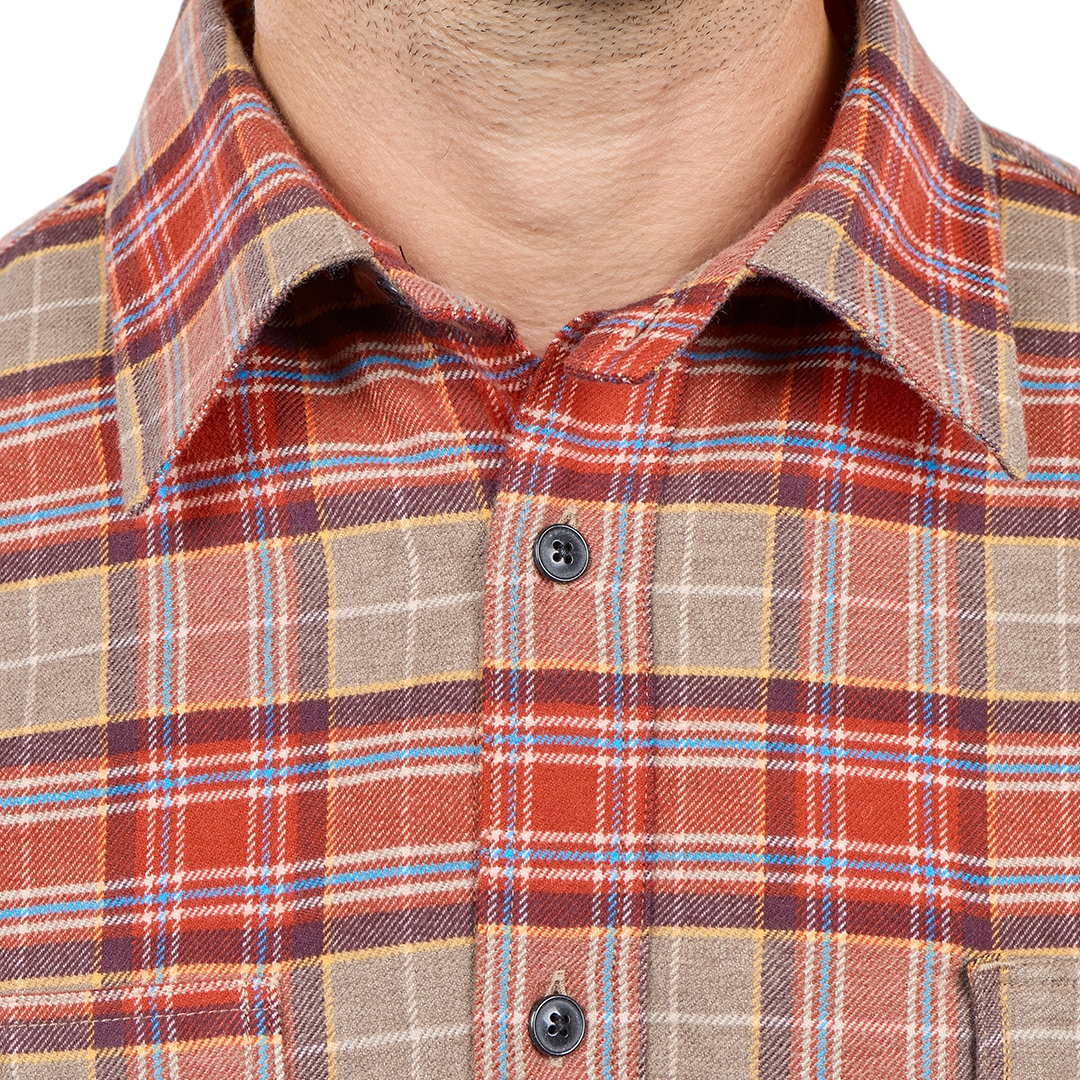 Close-up of a man wearing a collared plaid button-up shirt in rust red, tan, blue, and brown tones.