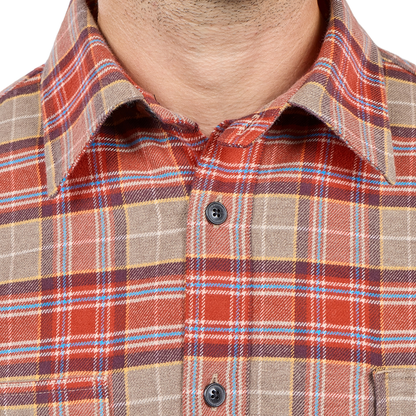 Close-up of a man wearing a collared plaid button-up shirt in rust red, tan, blue, and brown tones.