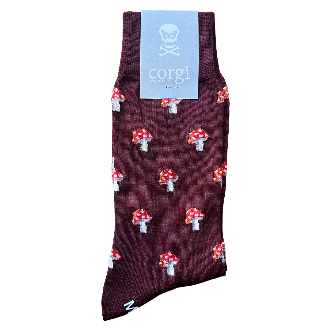 A single dark burgundy crew sock with an all-over red and white mushroom print, featuring a light blue paper tag with a skull and crossbones logo and the brand name 'corgi'.