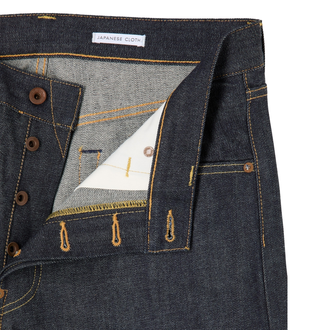 Close-up of a pair of dark indigo Japanese denim jeans showing the inner waistband, button closure, and detailed stitching.