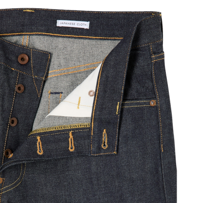 Close-up of a pair of dark indigo Japanese denim jeans showing the inner waistband, button closure, and detailed stitching.
