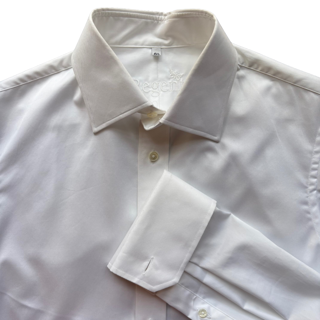 A close-up of a white long-sleeve dress shirt with a pointed collar, button front, and folded cuff, photographed against a bright white background.