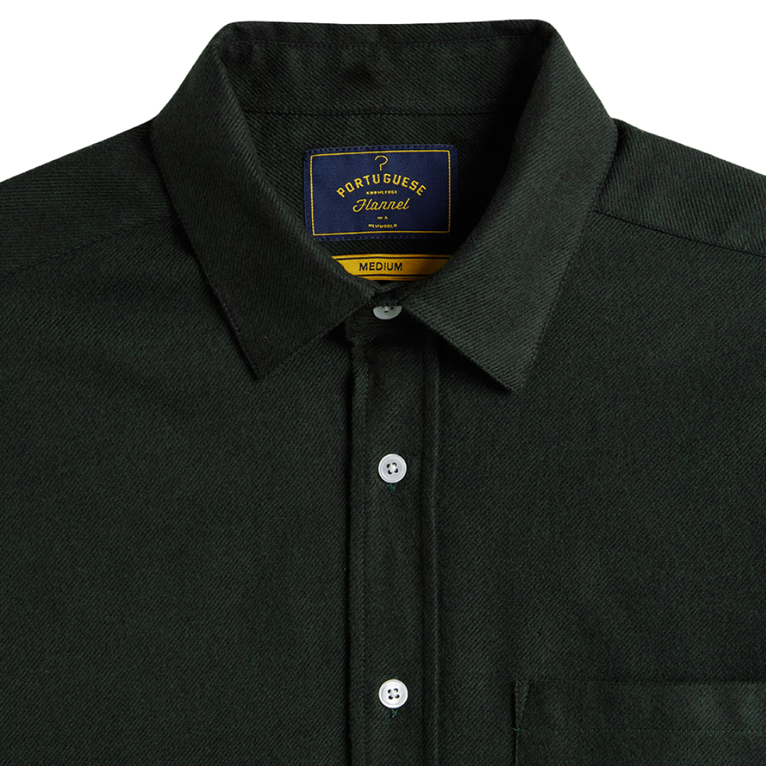 Close-up of a dark forest green Portuguese Flannel button-down shirt, showing the collar, white buttons, and the brand label inside the neck.