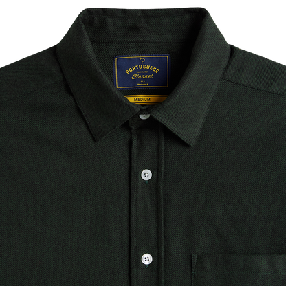 Close-up of a dark forest green Portuguese Flannel button-down shirt, showing the collar, white buttons, and the brand label inside the neck.