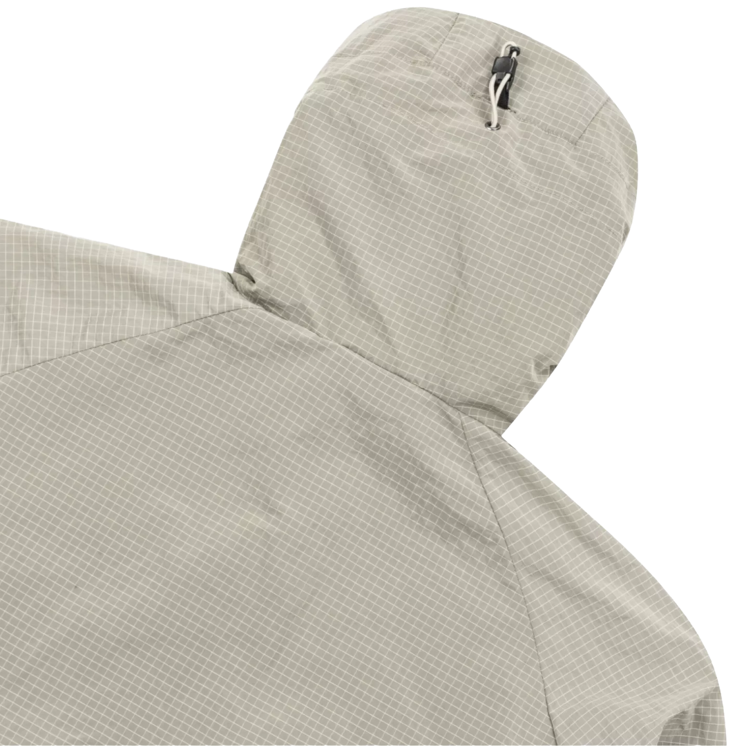 Close-up detail of a hooded jacket in a light beige and gray micro-check pattern, showing the top of the hood with a silver zipper pull against a white background.