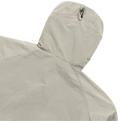 Close-up detail of a hooded jacket in a light beige and gray micro-check pattern, showing the top of the hood with a silver zipper pull against a white background.