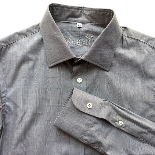 A close-up of a gray textured dress shirt with a spread collar and folded cuff, showing the inner neck label with 'by Regent' printed on it.