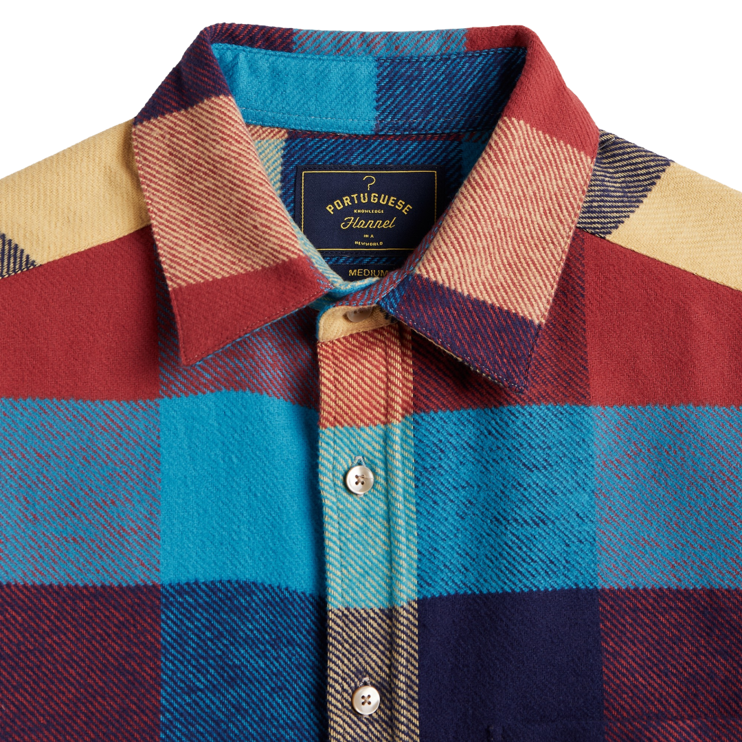 Close-up of a Port of Buenos Aires hand-dyed wool shirt jacket showing a multicolor plaid pattern with red, blue, navy, and beige blocks, featuring a button-down collar and front buttons.