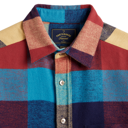 Close-up of a Port of Buenos Aires hand-dyed wool shirt jacket showing a multicolor plaid pattern with red, blue, navy, and beige blocks, featuring a button-down collar and front buttons.