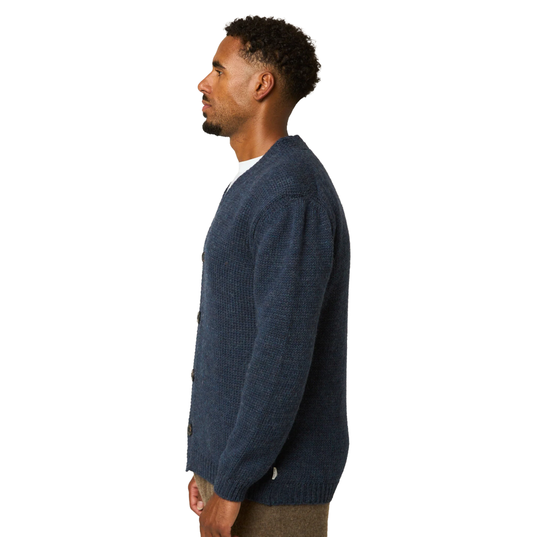 A man shown in profile wearing a dark navy blue knit cardigan over a white shirt, photographed against a solid white background.