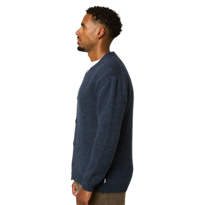 A man shown in profile wearing a dark navy blue knit cardigan over a white shirt, photographed against a solid white background.