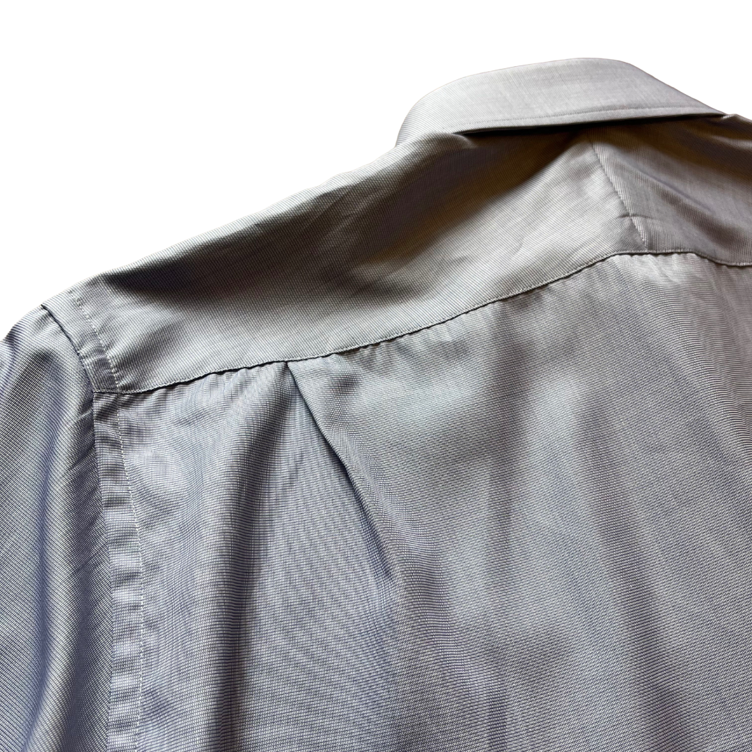 Close-up of the back of a light gray button-down shirt, showing the fabric texture, shoulder seam, and collar against a white background.