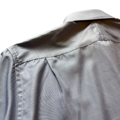Close-up of the back of a light gray button-down shirt, showing the fabric texture, shoulder seam, and collar against a white background.