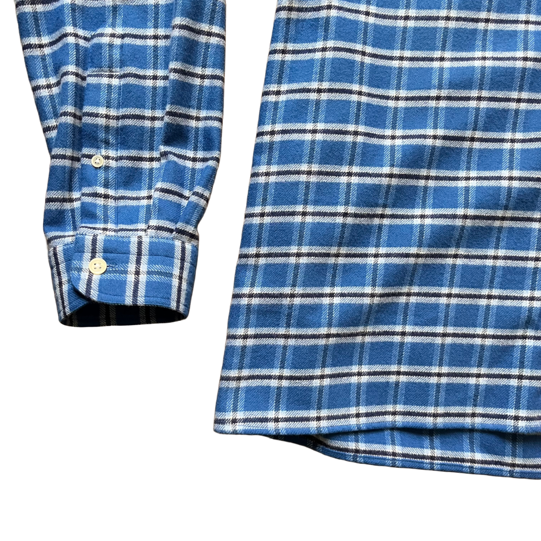 Close-up of a blue plaid flannel shirt showing the sleeve cuff with two buttons and a detailed view of the fabric pattern 