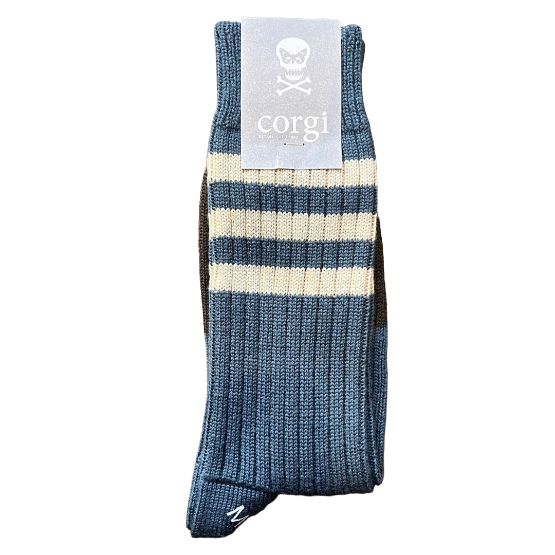 A single ribbed knit sock in blue and cream stripes, with a light gray paper tag attached at the top featuring a skull logo and the word 'corgi'.