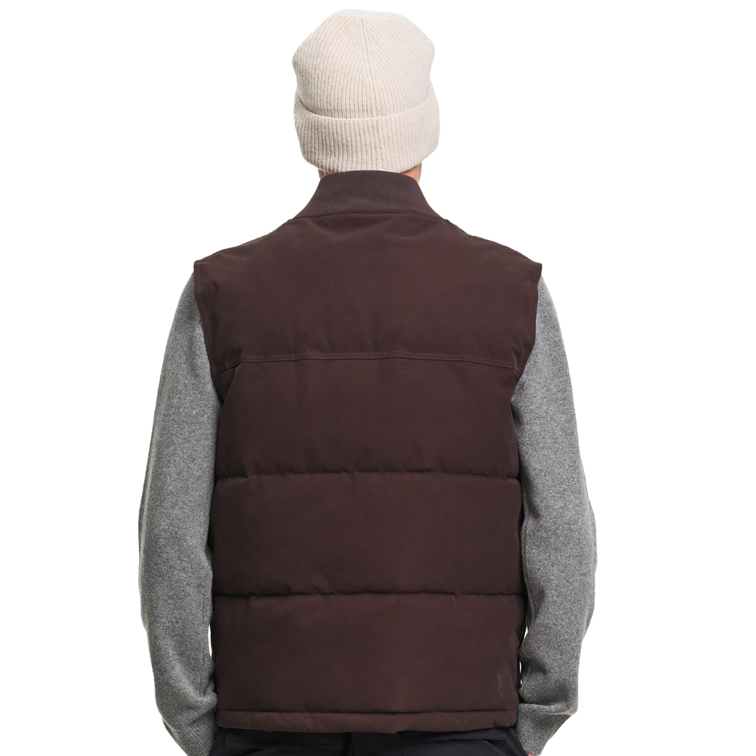 A person shown from the back wearing a dark brown puffer vest over a heather gray long-sleeve shirt, with a cream knit beanie on a plain white background.