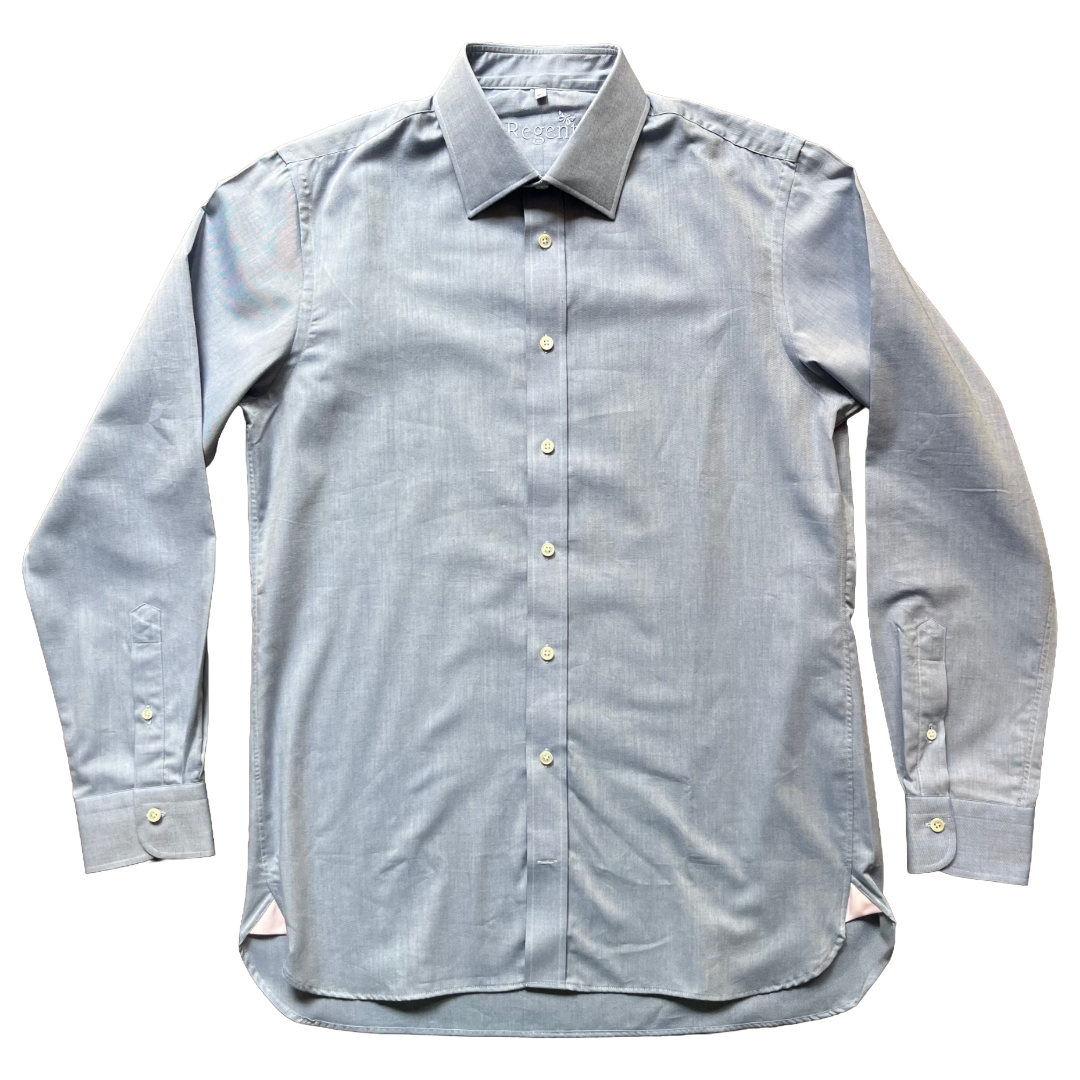 A light blue chambray long-sleeve button-down shirt with a pointed collar and light-colored buttons, laid flat against a white background.
