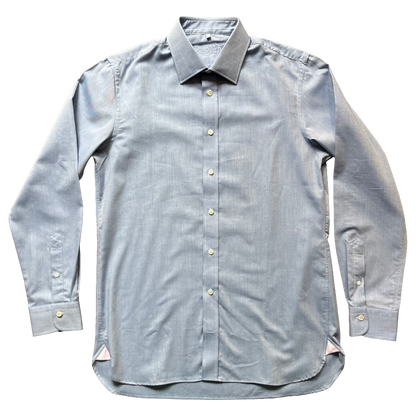 A light blue chambray long-sleeve button-down shirt with a pointed collar and light-colored buttons, laid flat against a white background.