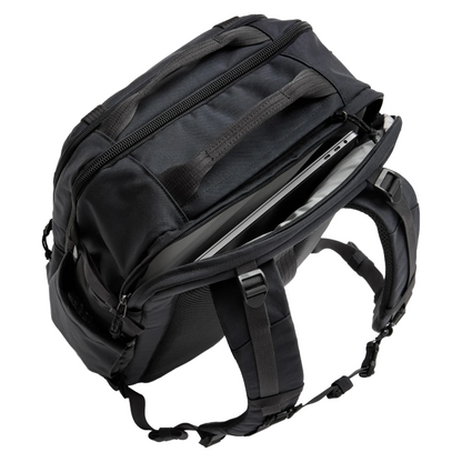 A black tactical backpack shown from an angled top view, with its main compartment open to reveal a silver laptop inside. The backpack features multiple zippered compartments, padded shoulder straps, and a structured, durable design, photographed against a solid white background.
