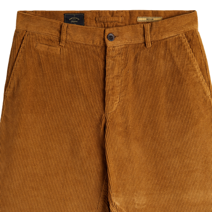 Close-up of a pair of corduroy trousers in a warm camel brown color, showing the waistband, button closure, belt loops, and front pockets.