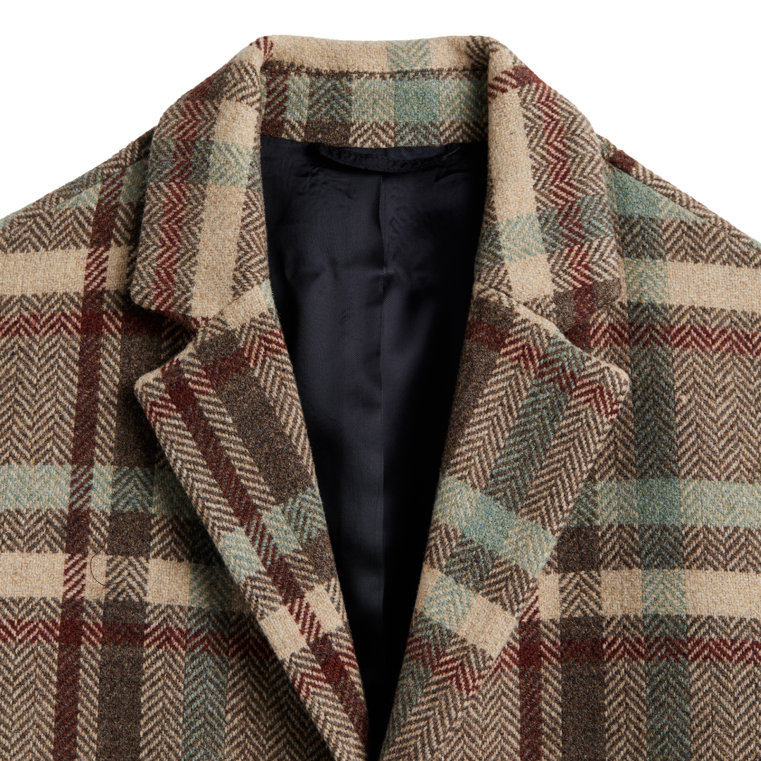 Close-up of a plaid wool coat with a black satin inner lining, featuring a beige, brown, and muted green herringbone pattern.