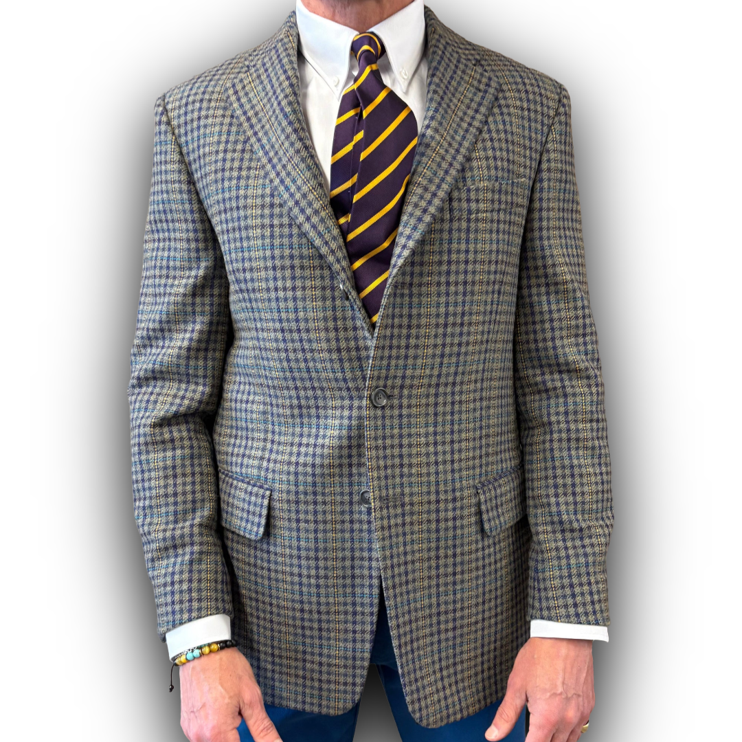 Tweed yellow/nlue/grey suit jacket with a striped tie on a plain background