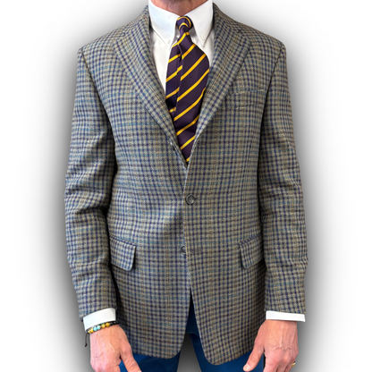 Tweed yellow/nlue/grey suit jacket with a striped tie on a plain background