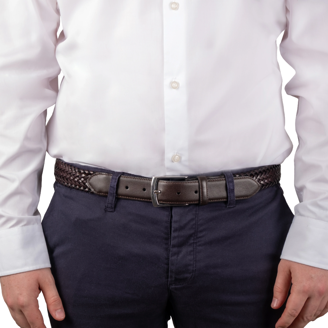 A close-up of a person wearing a dark brown woven belt with a dark brown leather buckle, paired with navy blue trousers and a white button-down shirt.