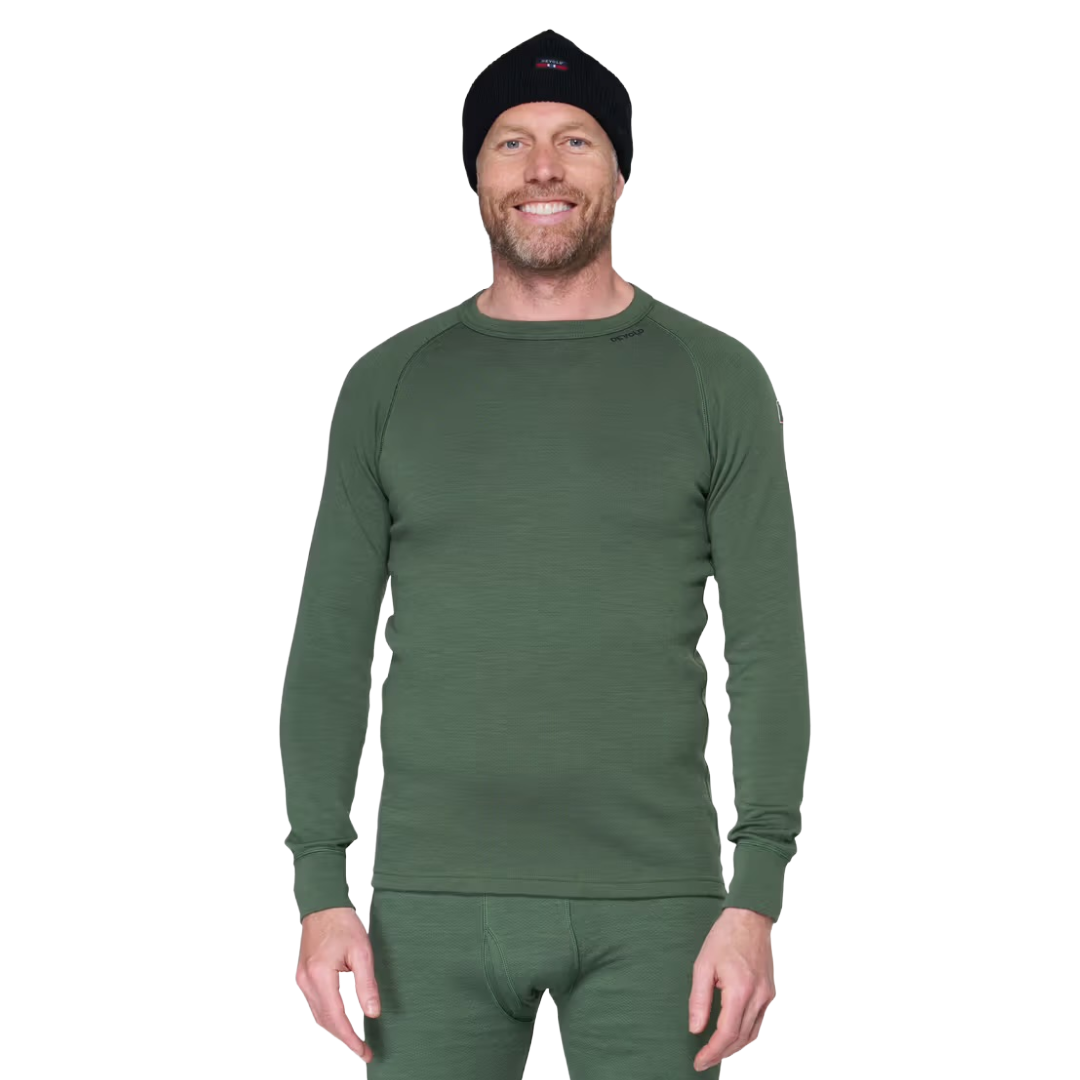 A man wearing a dark green long-sleeve thermal underwear top and matching green pants, along with a black knit beanie, photographed against a plain white background.