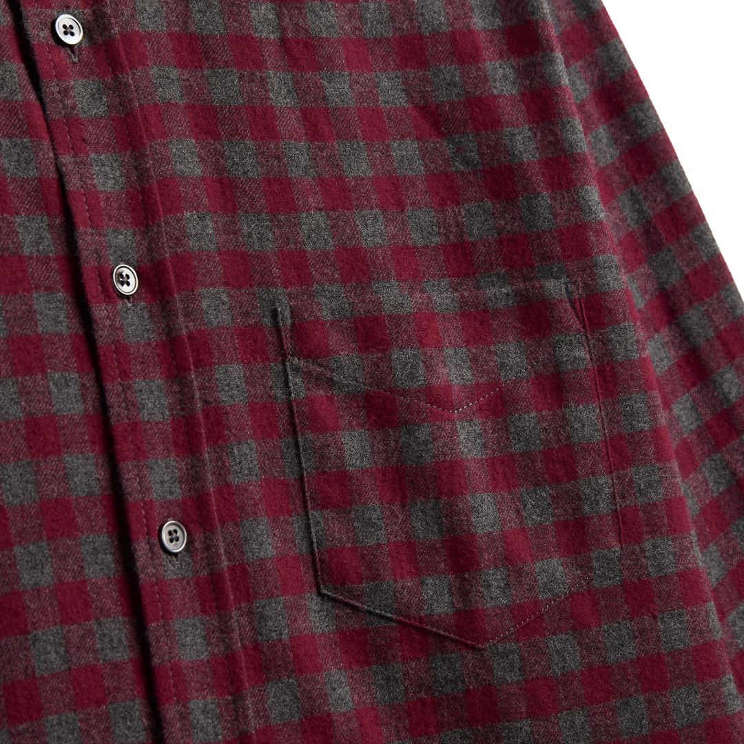 Close-up of a red and dark gray buffalo check plaid flannel shirt with a chest pocket and metal snap buttons.