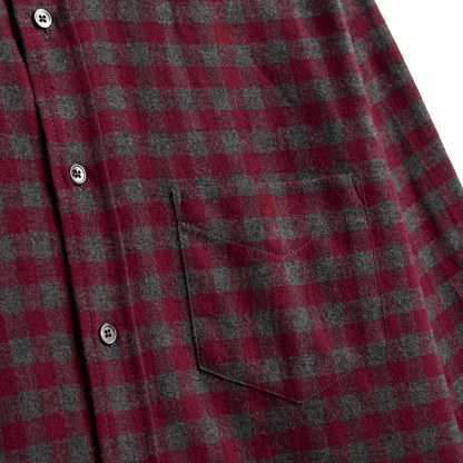 Close-up of a red and dark gray buffalo check plaid flannel shirt with a chest pocket and metal snap buttons.