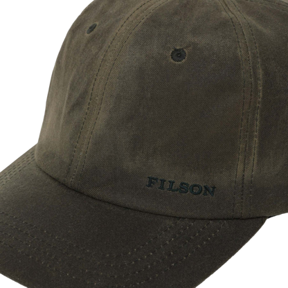 Close-up of a dark olive green Filson baseball cap on a white background, showing the embroidered brand name on the brim.