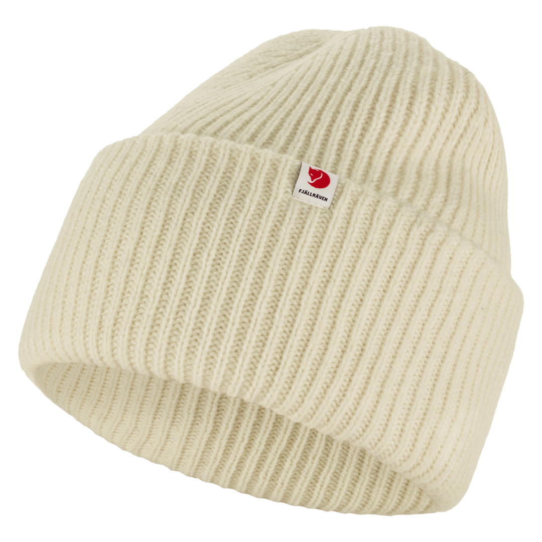 A cream-colored ribbed knit beanie hat with a small red and white Fjällröven logo patch on the front cuff, shown against a plain white background.
