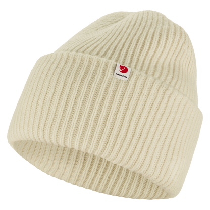 A cream-colored ribbed knit beanie hat with a small red and white Fjällröven logo patch on the front cuff, shown against a plain white background.