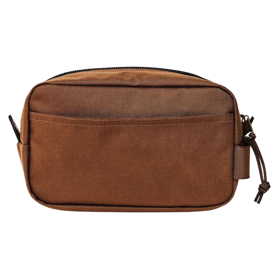 A brown canvas toiletry bag with a top zipper, front slip pocket, and side strap closure, shown against a plain white background.