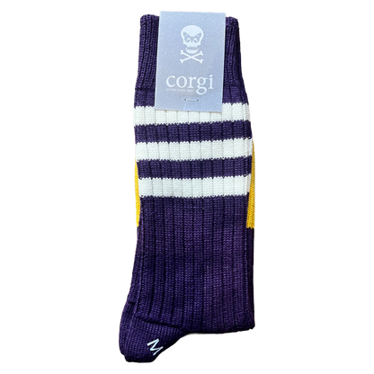 A single purple ribbed knit sock with white and yellow stripes, featuring a light blue paper tag with a skull and crossbones logo and the brand name 'corgi'.