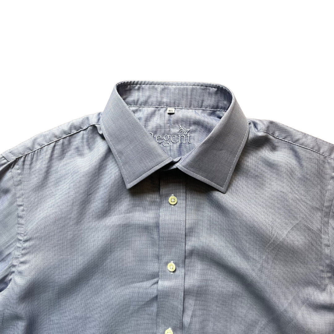 A close-up of a light gray micro-patterned dress shirt with a pointed collar and light-colored buttons, laid flat against a white background.