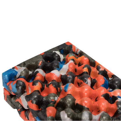 A close-up of a textured, bubbled material sample with a multicolor pattern of bright orange, black, white, and blue on a plain white background.