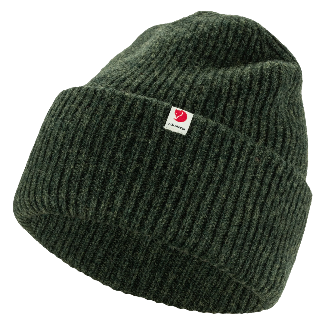 A dark green ribbed knit beanie hat with a small white square brand tag on the front cuff.