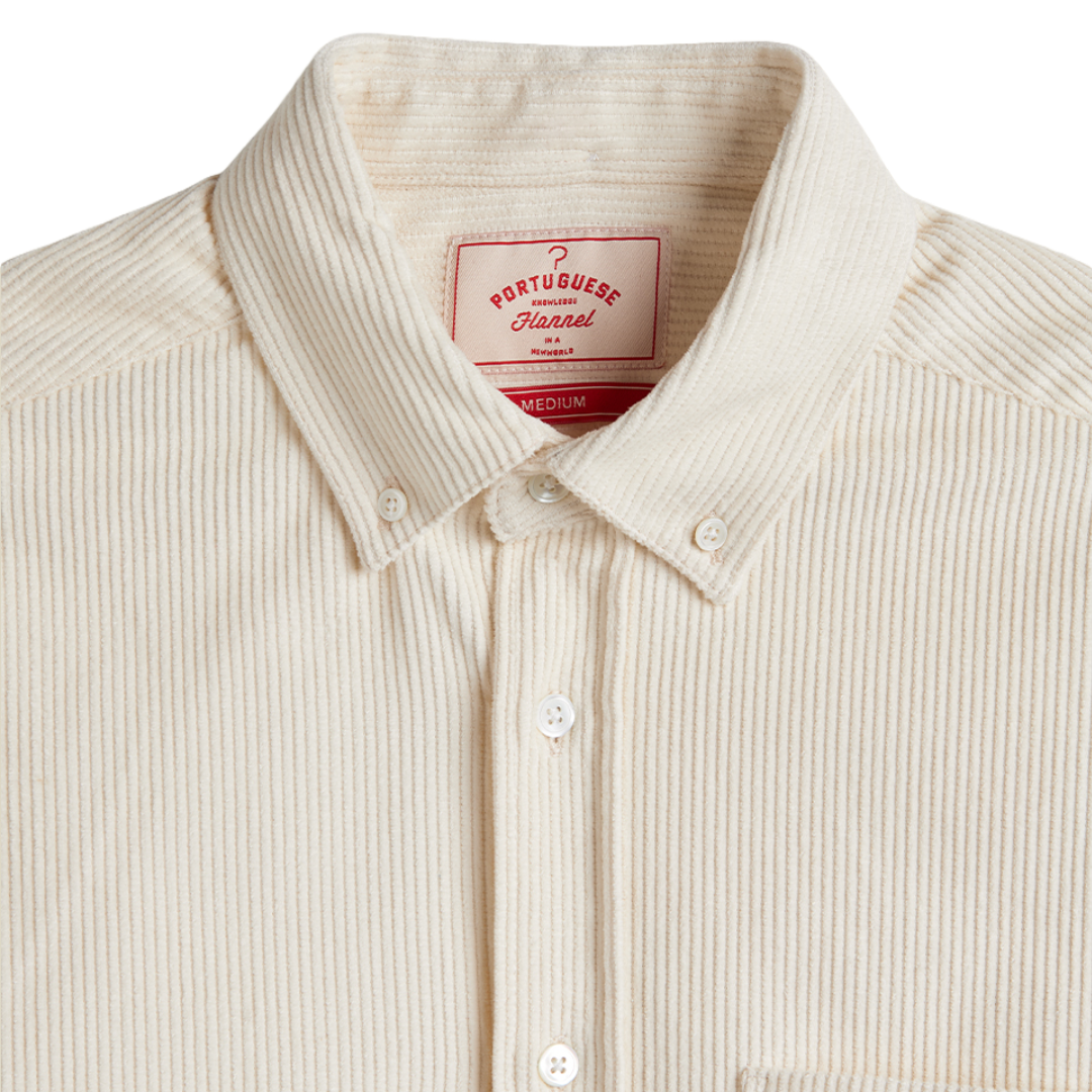 Close-up of a cream-colored Portugueseannel button-down shirt with a ribbed corduroy-like texture, featuring a pointed collar and white buttons.